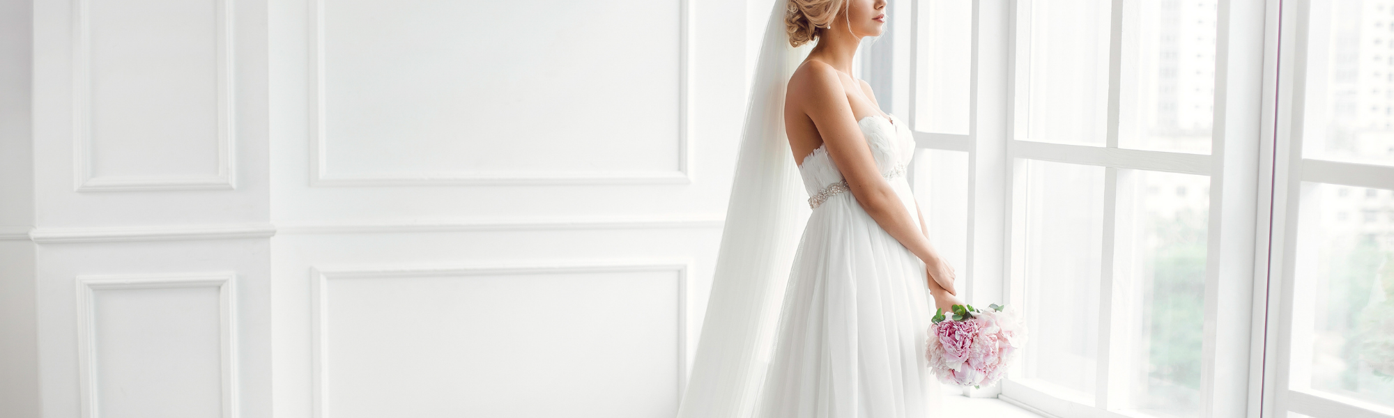 bride in a white dress looking out a window